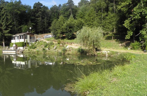 Augignac Ski Chalet | Chalet overlooking a pond in a green setting.